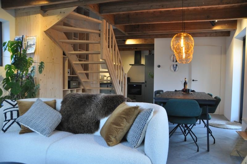 Wohnzimmer mit Sofa, Esstisch und Holztreppe